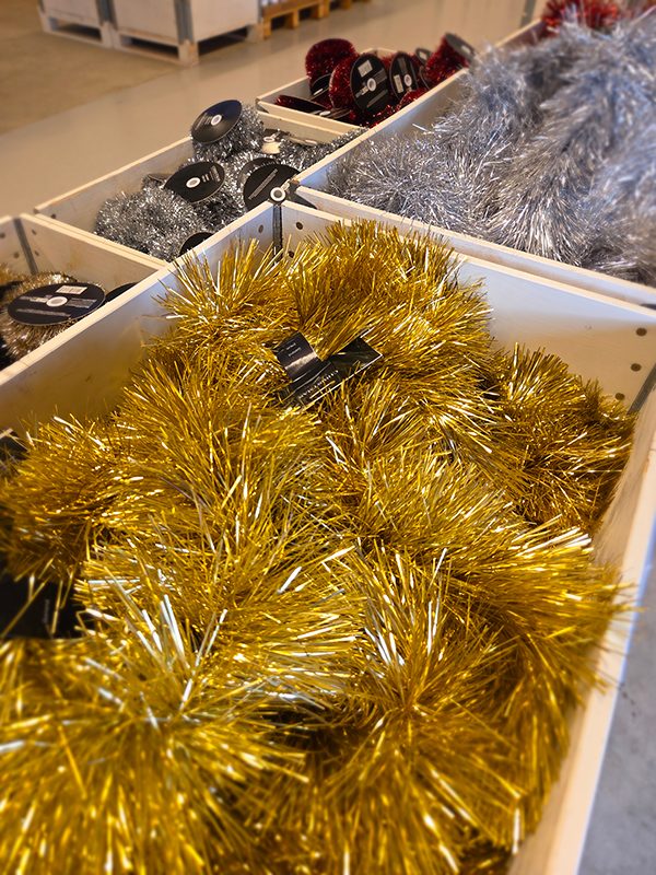 Plastjulgran dekorerad med röda kulor och guldslingor i julmiljö