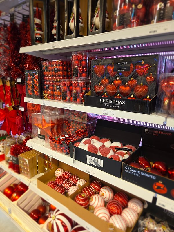 Plastjulgran dekorerad med röda kulor och guldslingor i julmiljö