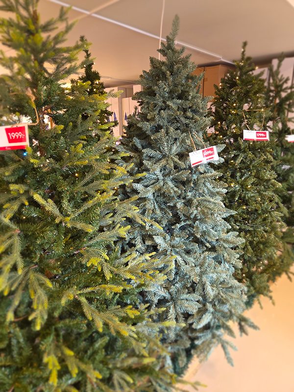 Plastjulgran dekorerad med röda kulor och guldslingor i julmiljö