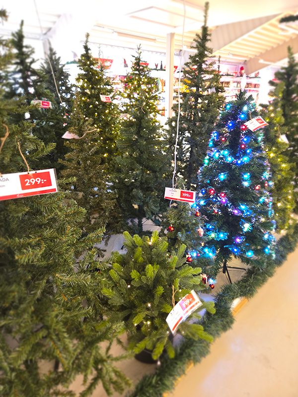 Plastjulgran dekorerad med röda kulor och guldslingor i julmiljö